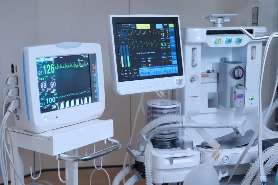 Close-up of modern medical equipment: a patient monitor displaying vital signs and a ventilator with screens showing waveforms.