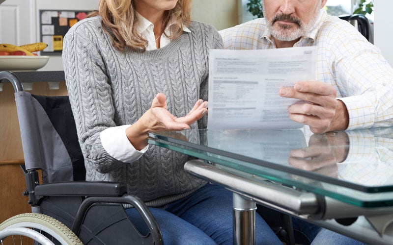 A woman in a wheelchair discusses a document with a man at a table.