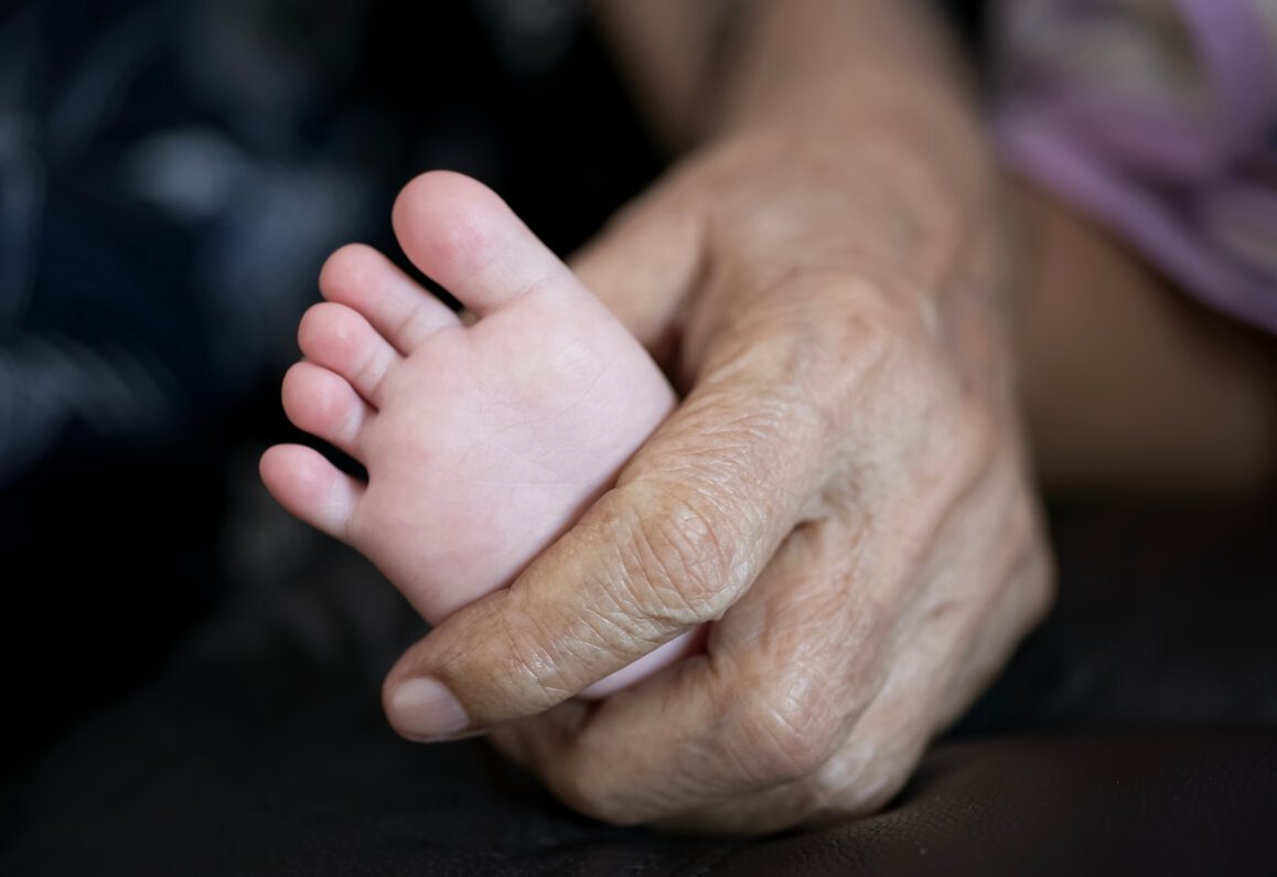 Grandfather holding grandchild's foot.